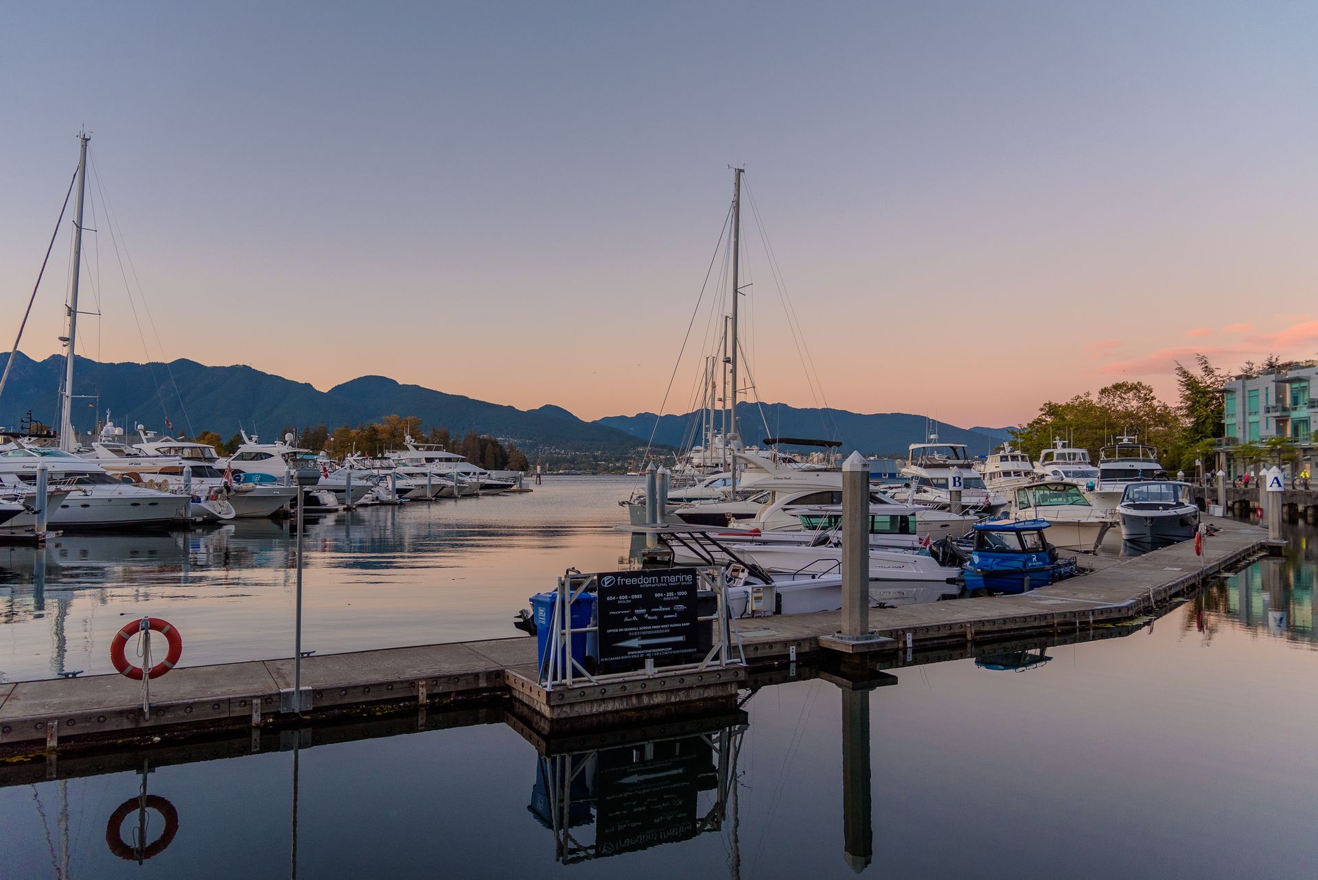 Yachts at a marina at sunset with mountains behind